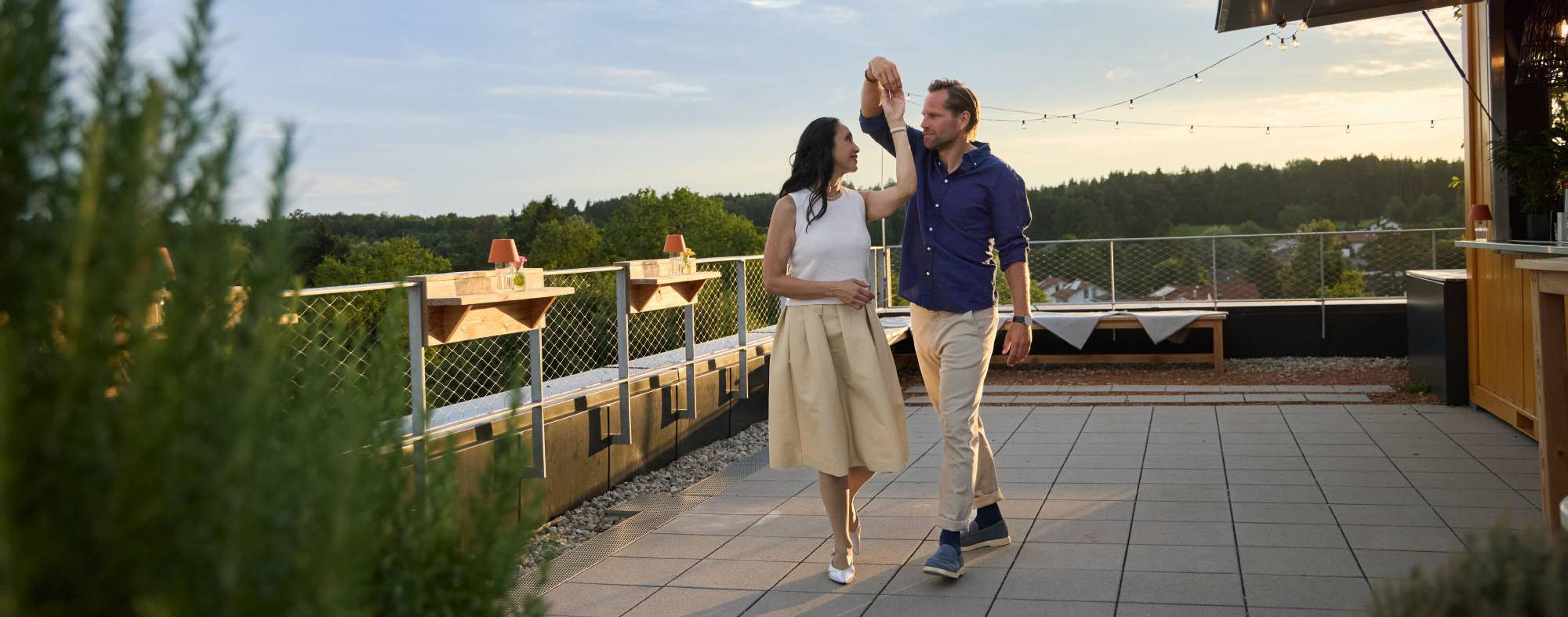 Kompression im Sommer. Eine Frau und ein Mann tanzen auf einer Dachterrasse.
