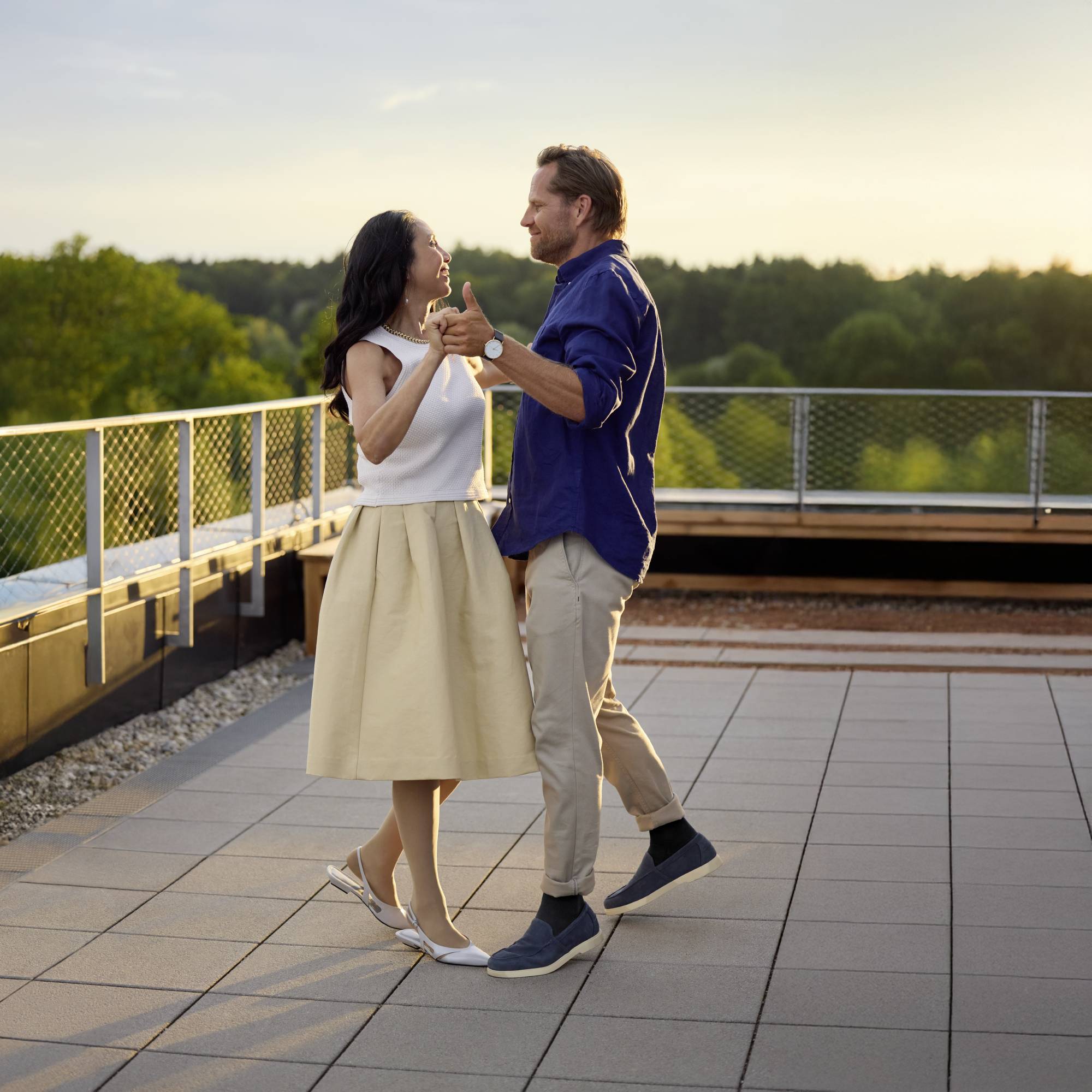 Frau mit Kompressionsversorgung tanzt mit Mann im Sommer auf Dachterrasse