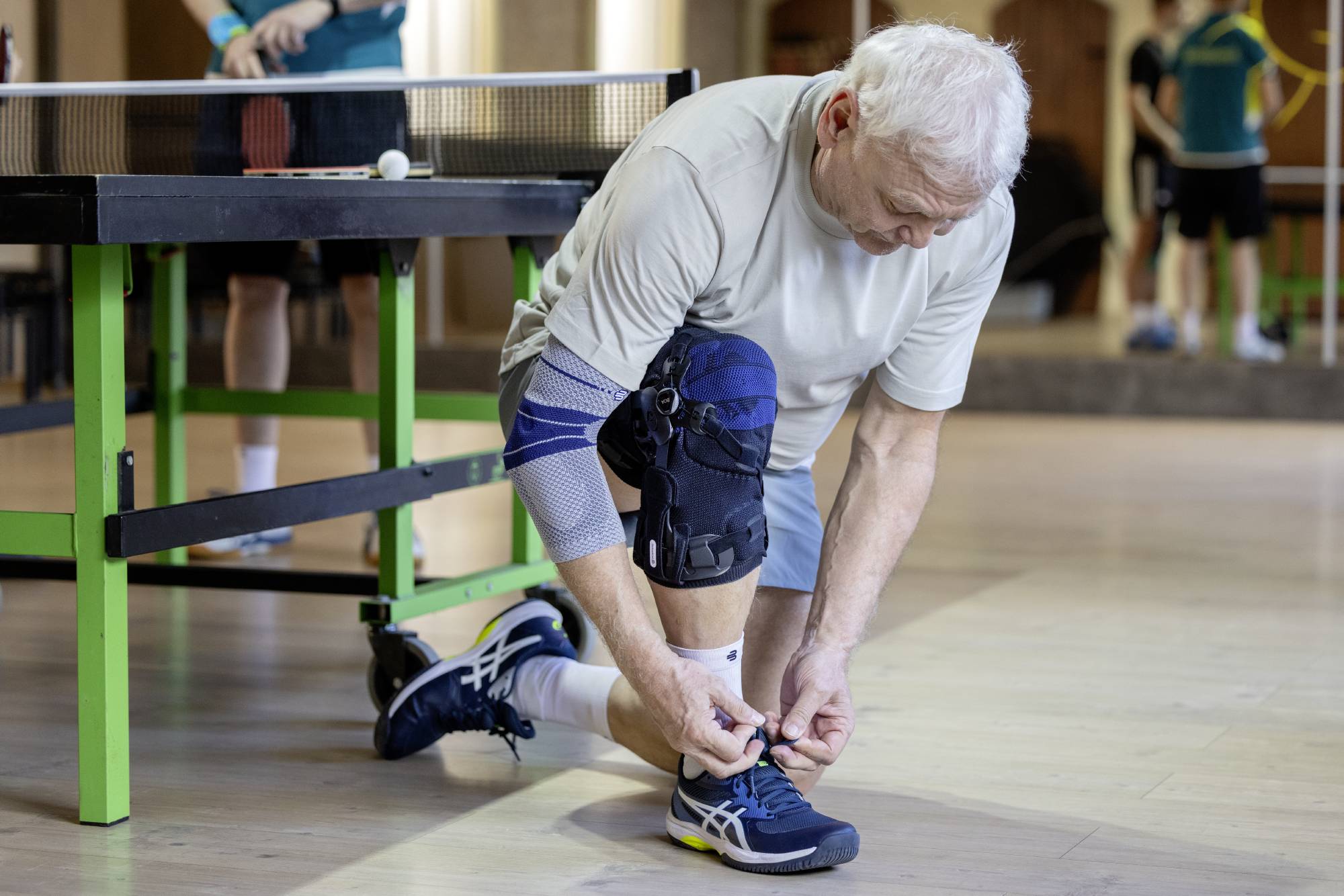Mann beim Tischtennis mit GenuTrain Knieorthese von Bauerfeind