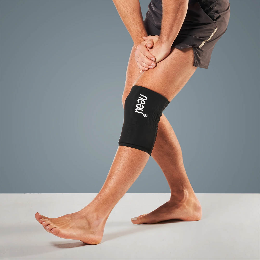 Mann in Sportkleidung trägt Kühlpad am linken Knie